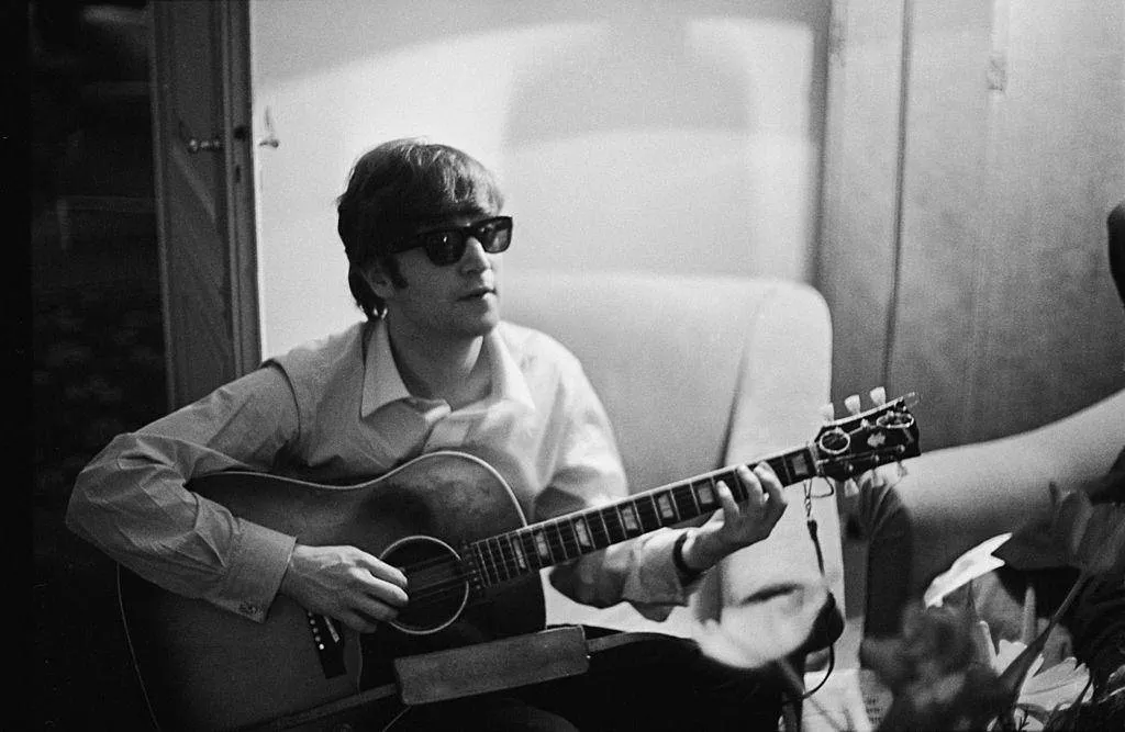 Lennon playing the guitar with sunglasses