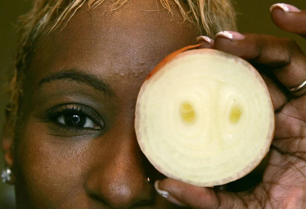 A woman holds up a white onion in front of her eye.