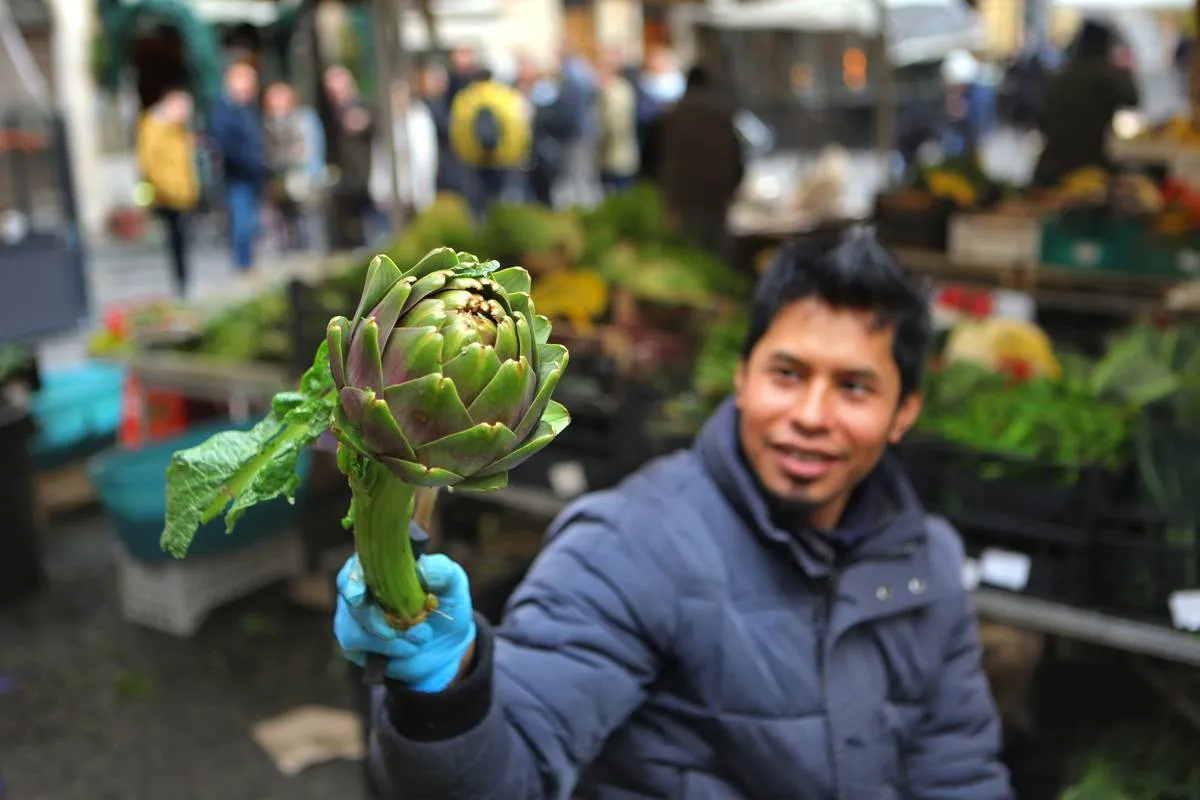 A man holds an artichoke at a market.