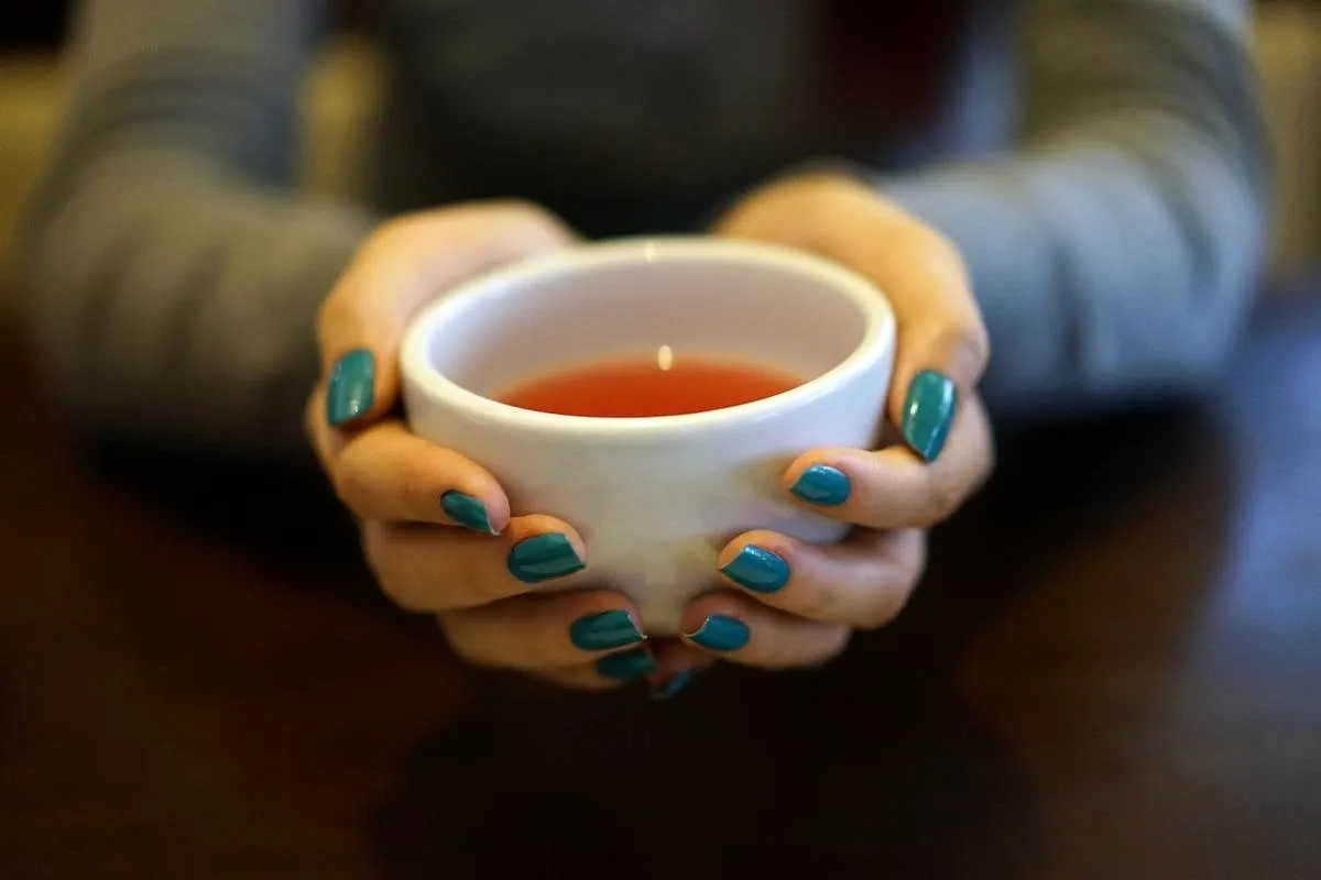 A woman holds a cup of tea.