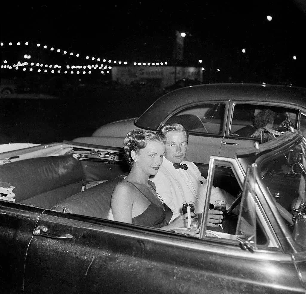 a 50s couple sitting in a convertible