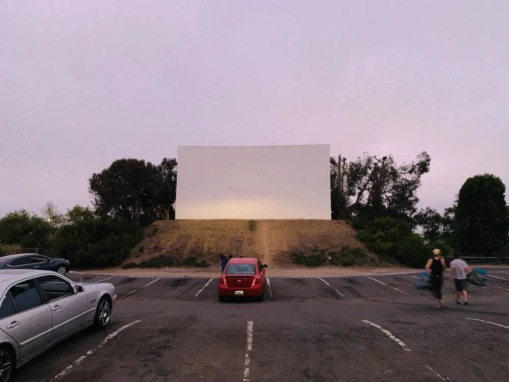 a red car parked in front of a drive-in screen