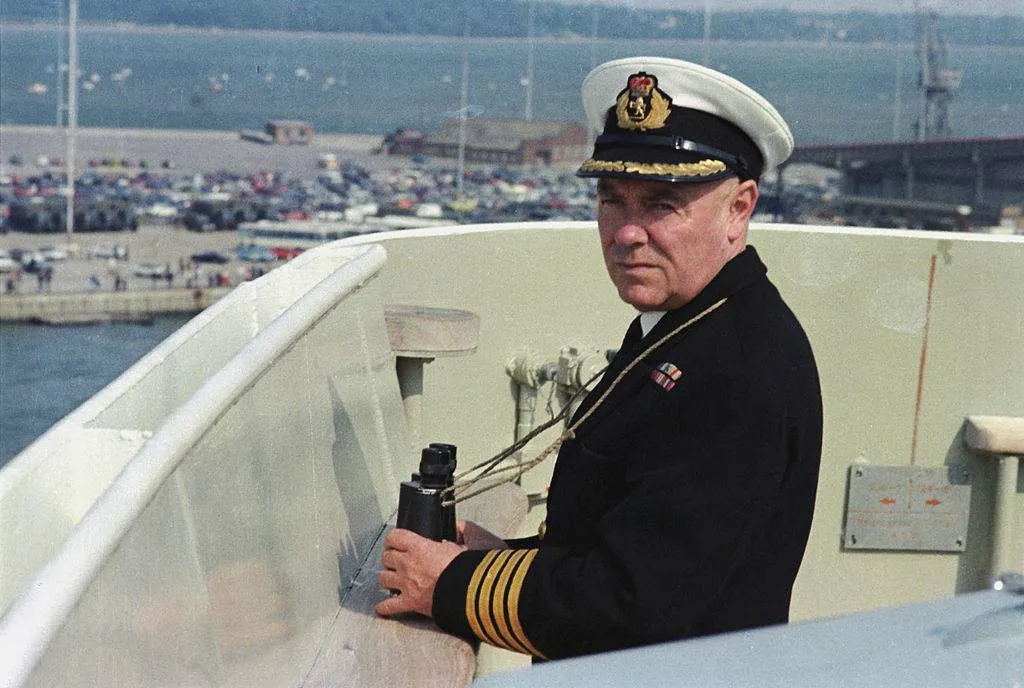 A captain looks to sea from a ship.