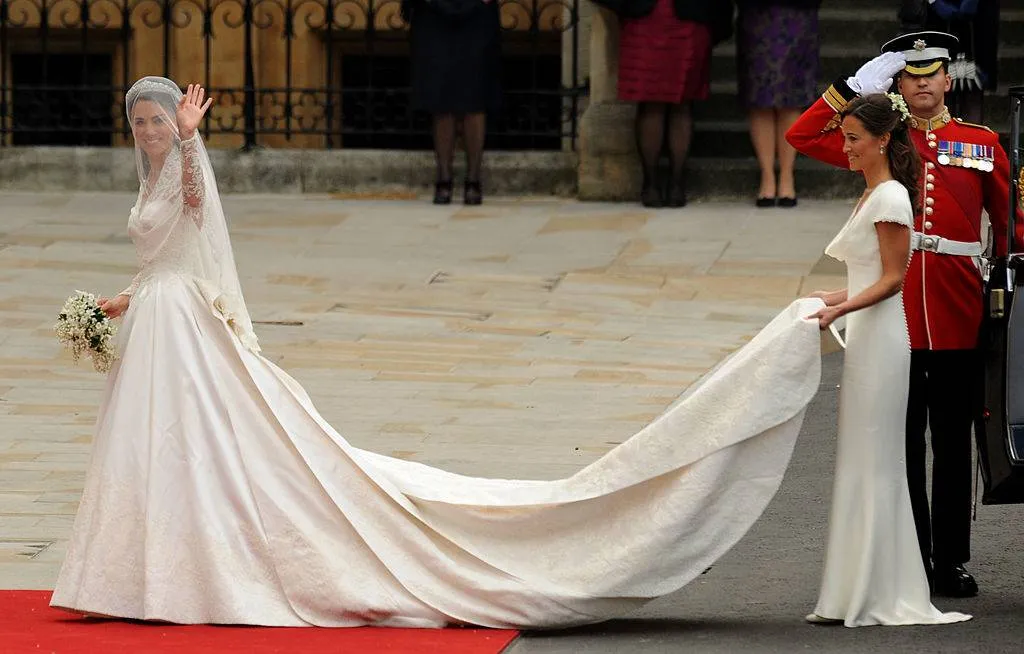Kate Middleton (L) waves as she arrives with her sister, the Maid of Honour Philippa Middleton at the West Door of Westminster Abbey