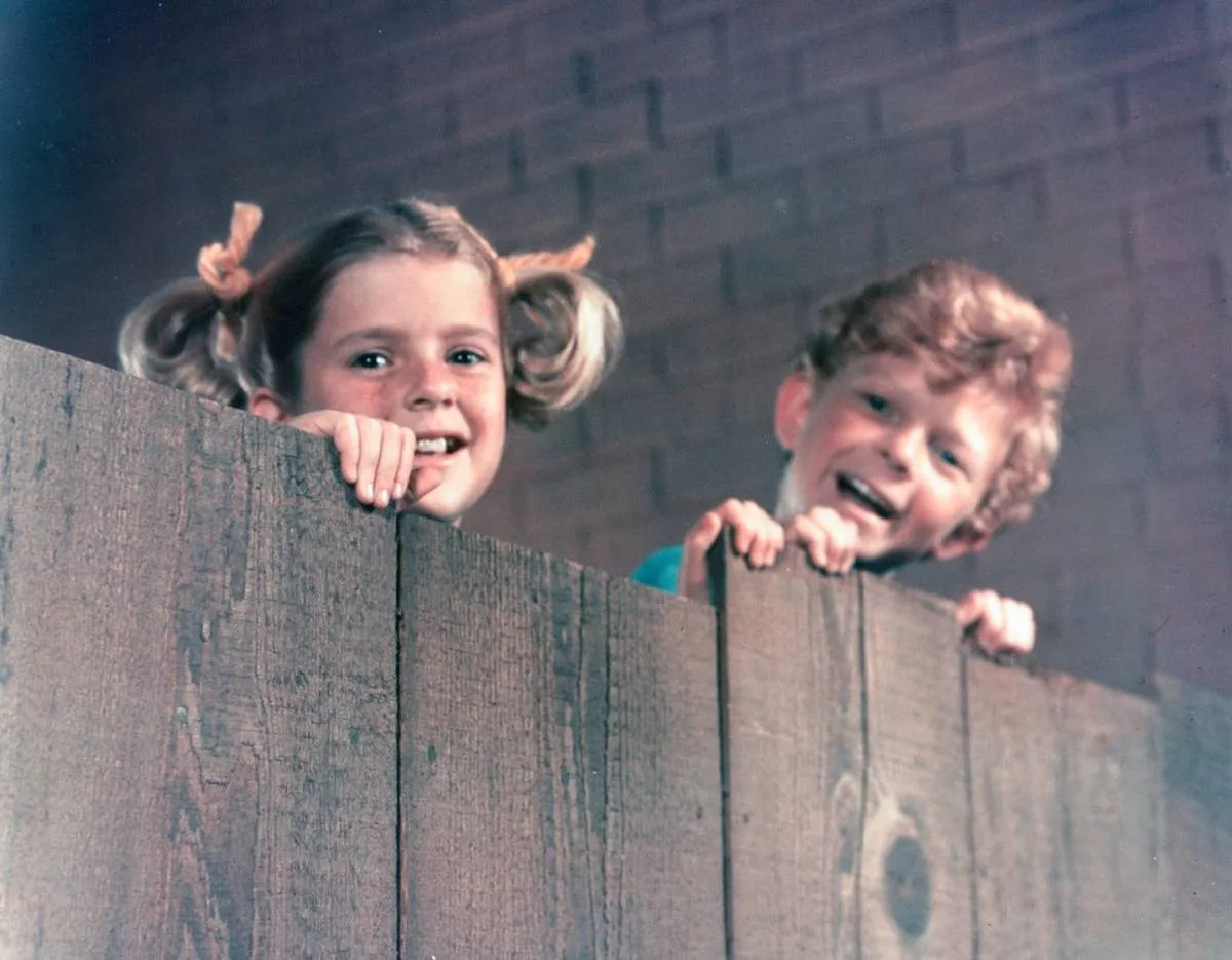 Actress Anissa Jones and Johnny Whitaker peer over a fence during the filming 'Family Affair.'