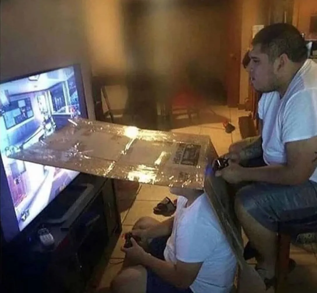 people playing splitscreen video game use cardboard divider to ensure the two players can't see each others' screens