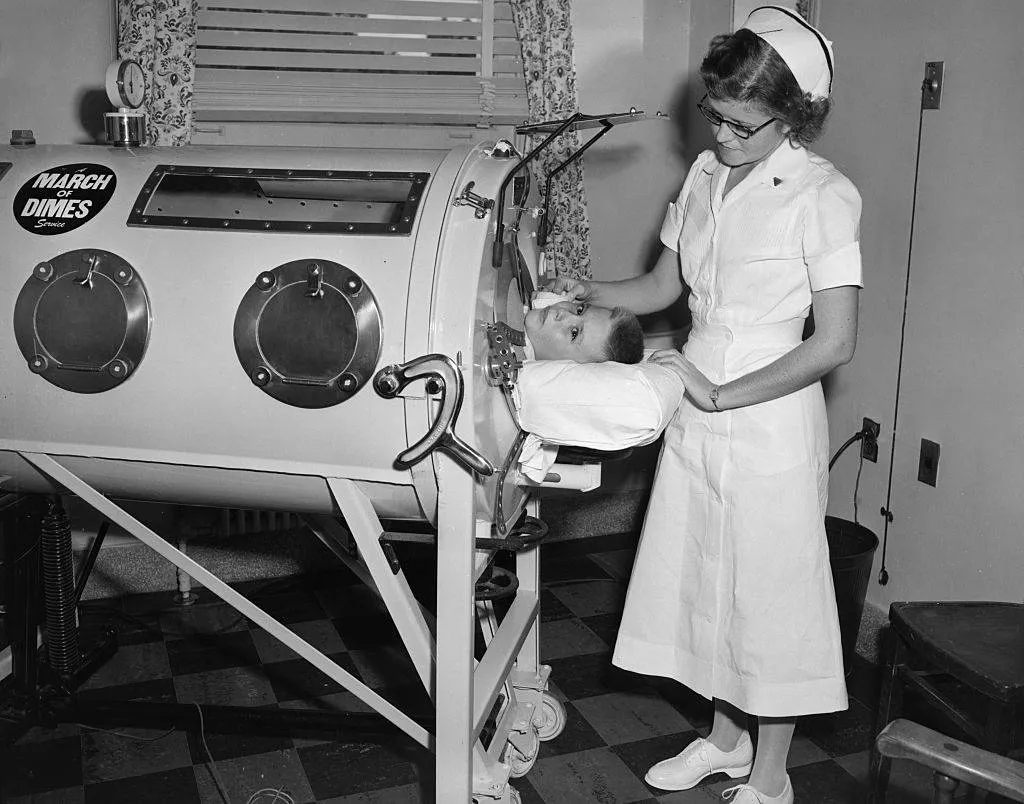 An iron lung sponsored by the March of Dimes helps a young boy with polio breath during the 1950s.