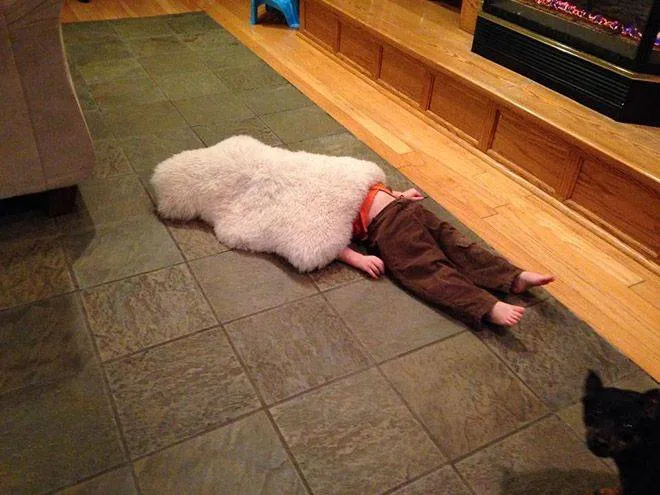 kid half hiding under rug
