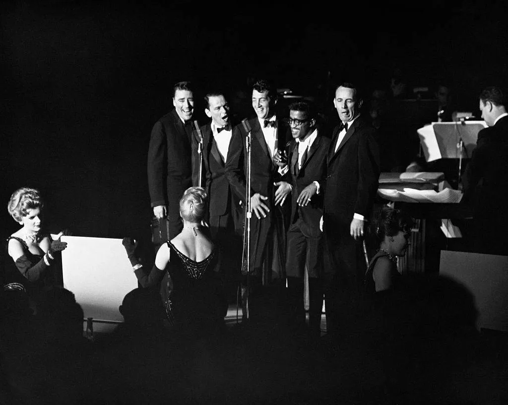 Peter Lawford, Frank Sinatra, Dean Martin, Sammy Davis Jr., and Joey Bishop performing.