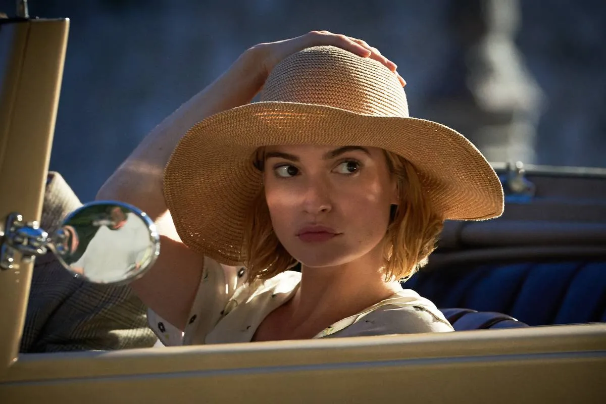 lily james sitting in a car wearing a hat in rebecca