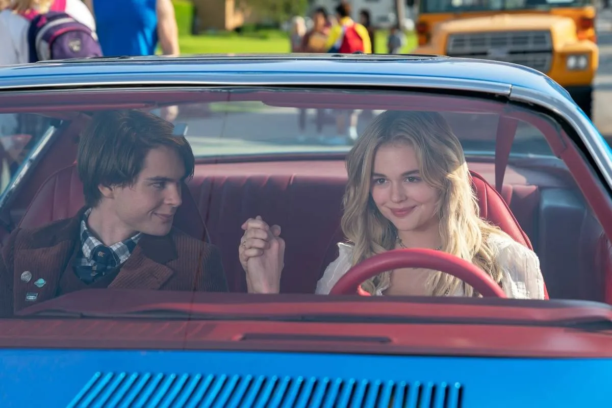 two teenagers holding hands inside a car in the babysitter killer queen
