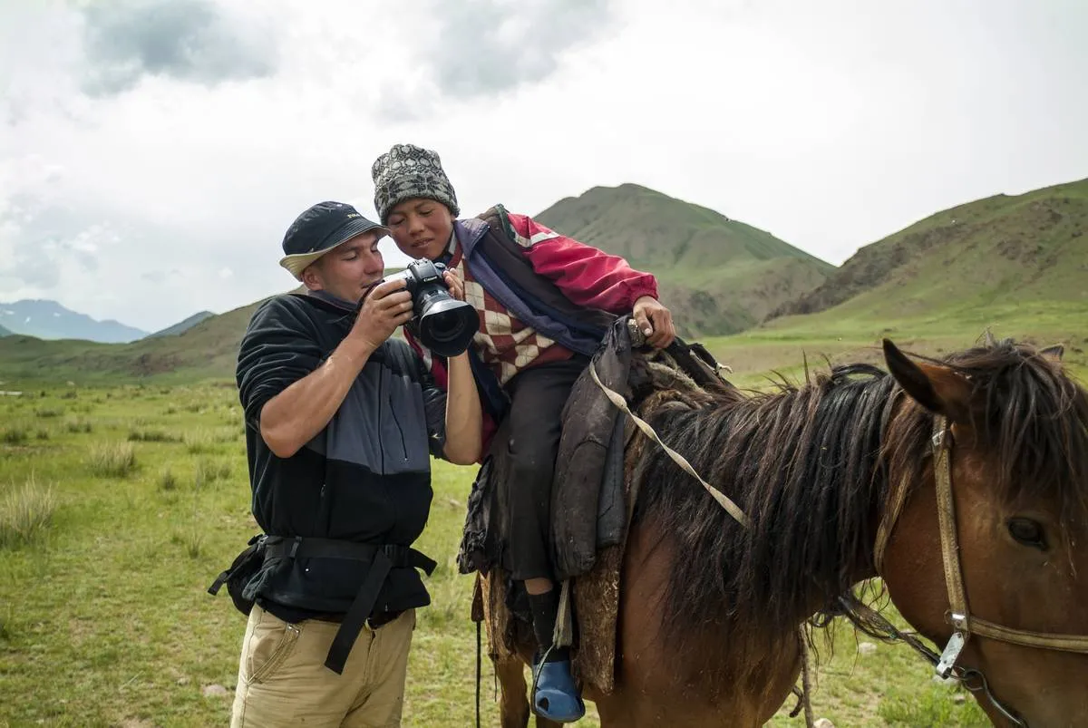 A foreigner shows a young Kyrgyz boy images on his digital...