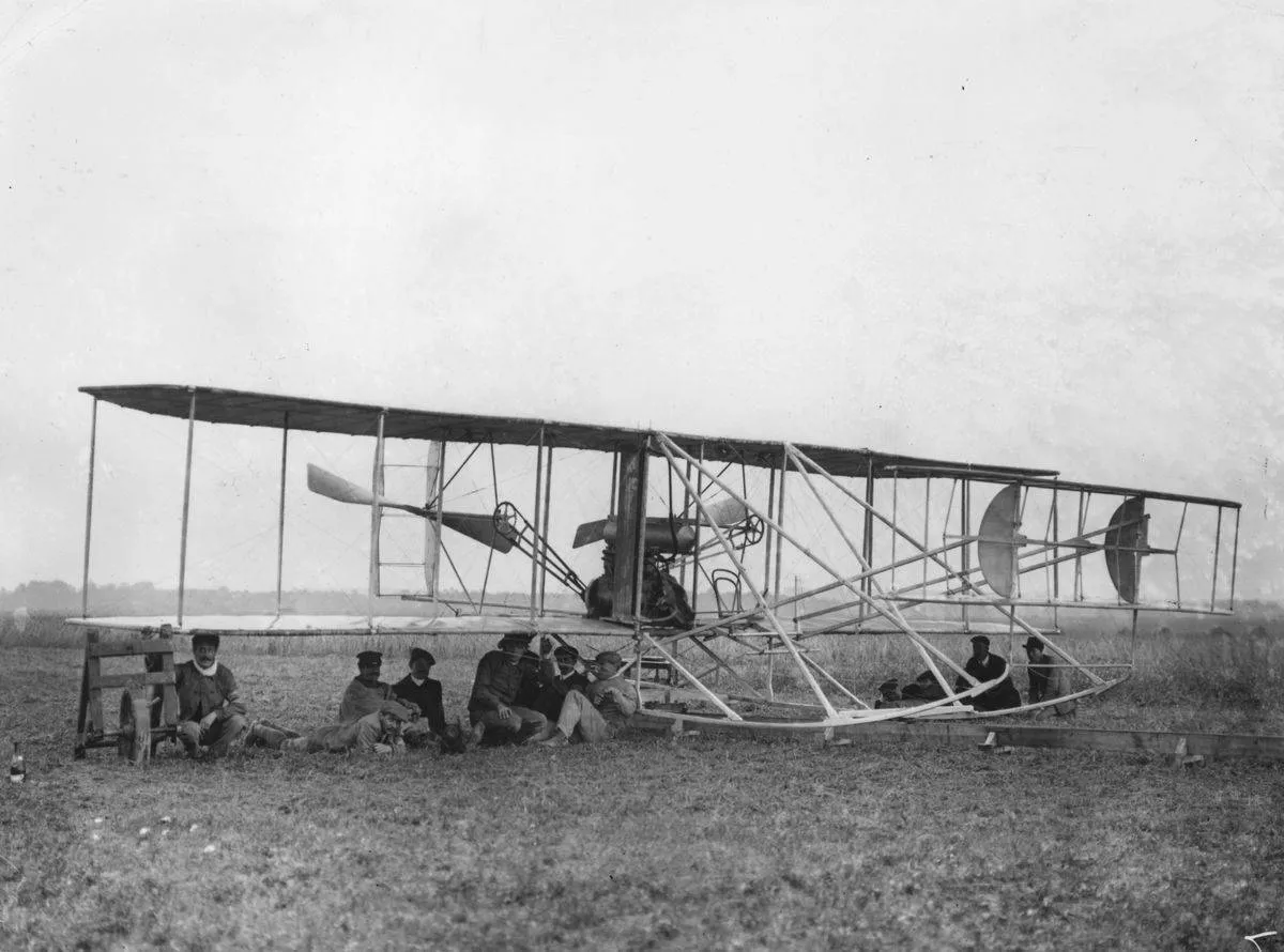 A group of men shelter under Eugene Lefebvre's Wright Type A Flyer.