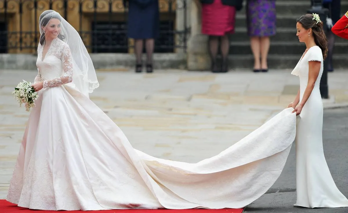 Kate Middleton walks toward her wedding as her sister spreads out her wedding dress.