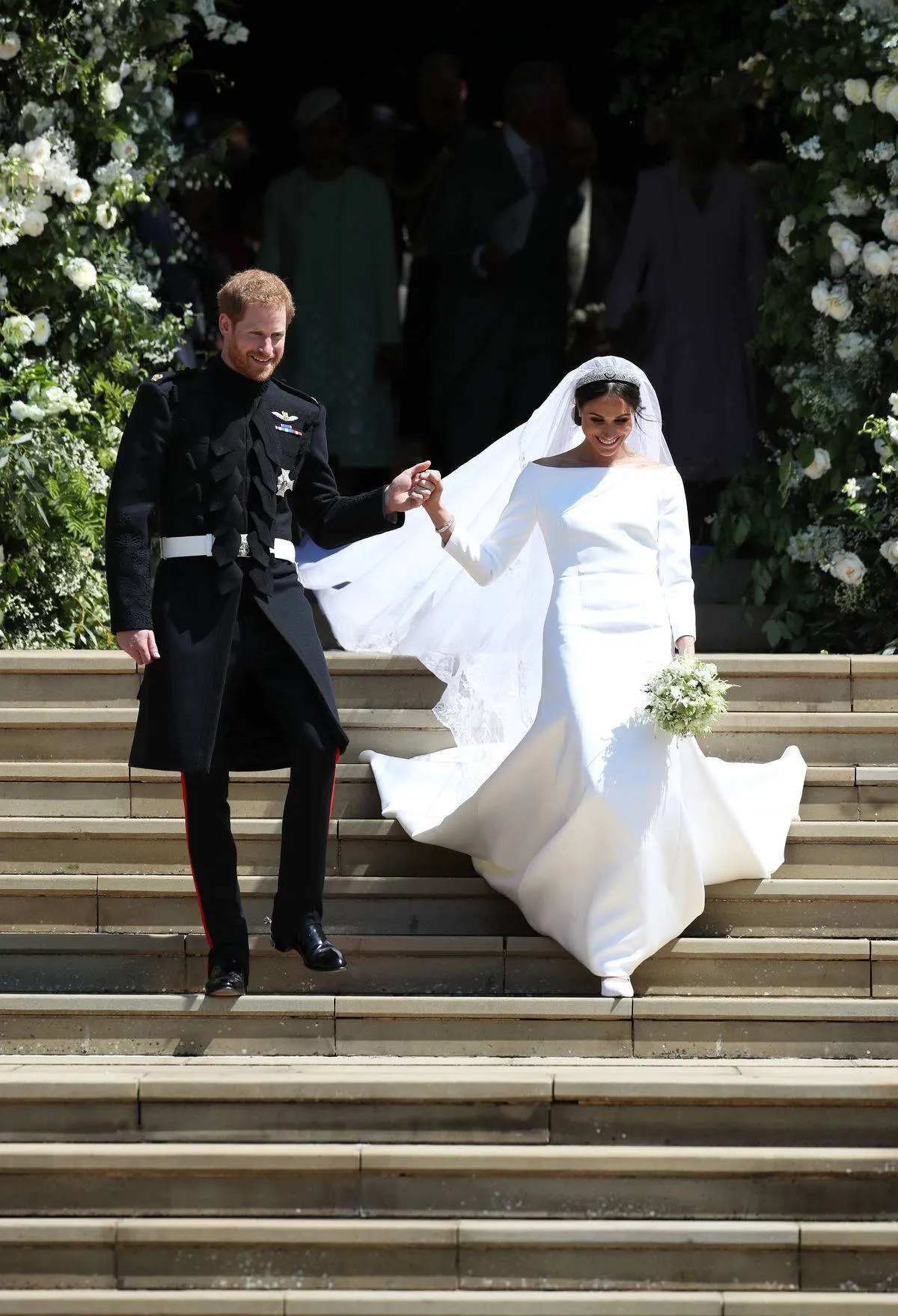 Prince Harry and Meghan Markle walk down the Windsor castle stairs after getting married.