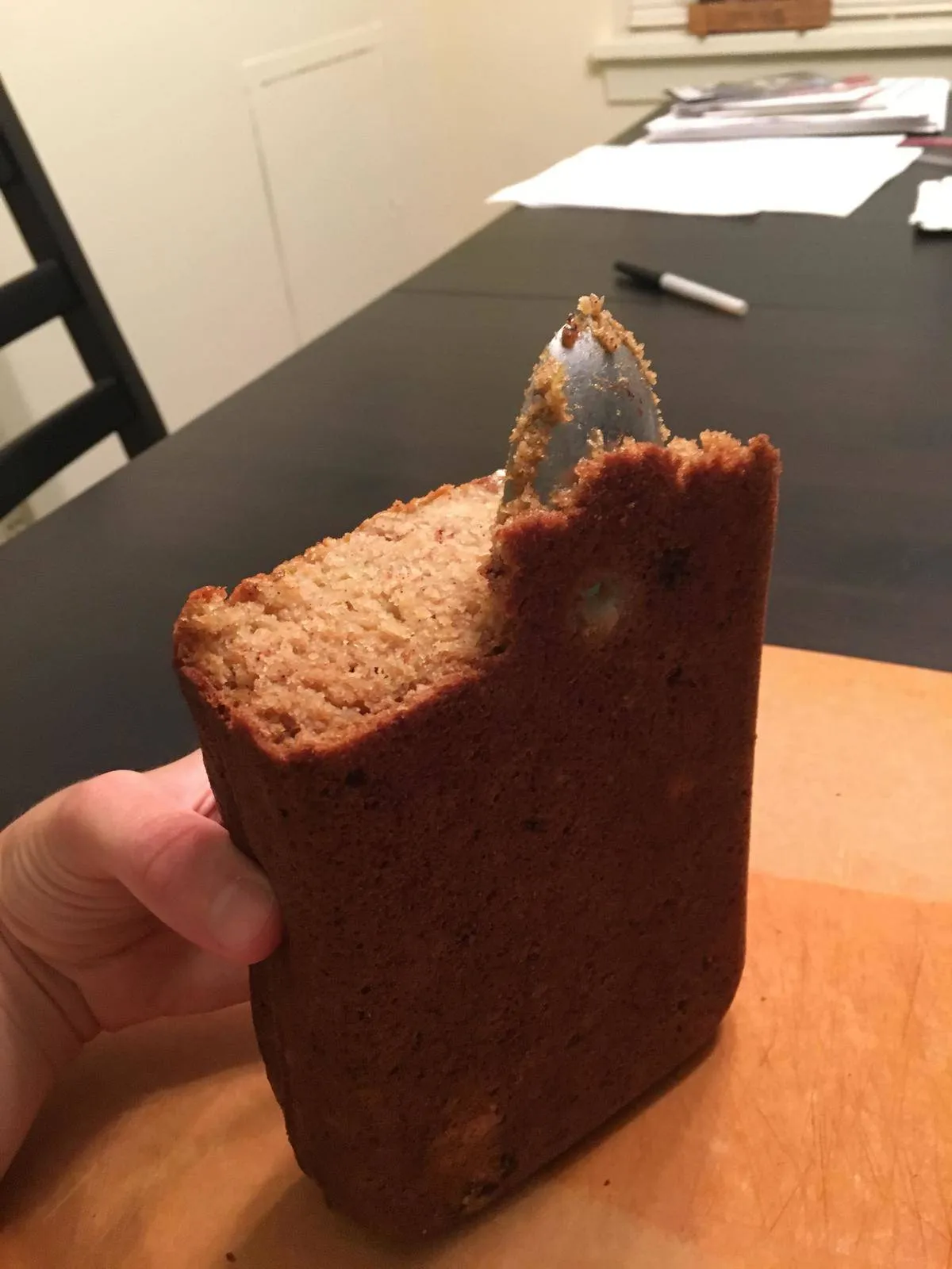 someone holding a homemade loaf of bread with a spoon sticking out 