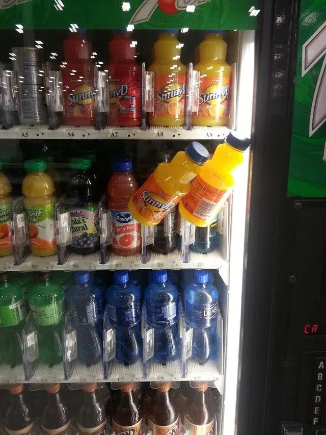 two Sunny D's leaning against the glass of a vending machine  