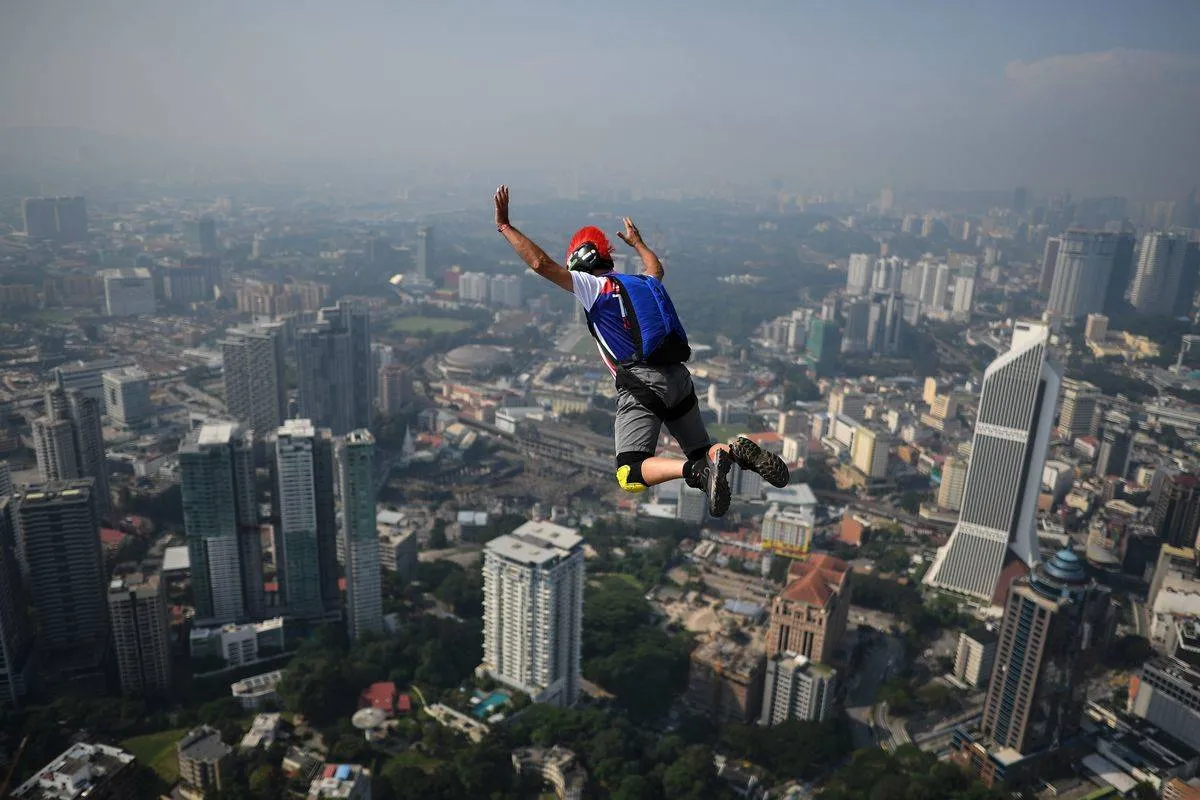 A person base jumps off of a 300-meter high skyscraper in Malaysia.