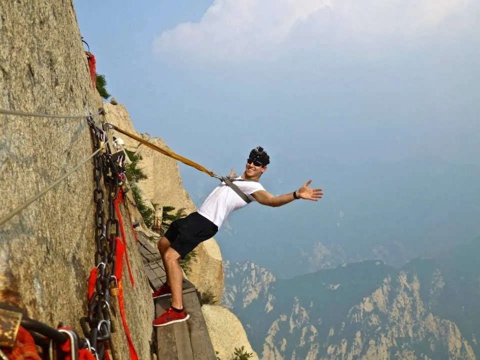 A hiker dangles off the narrow Plank Walk of the Hua Shan Trail in China.