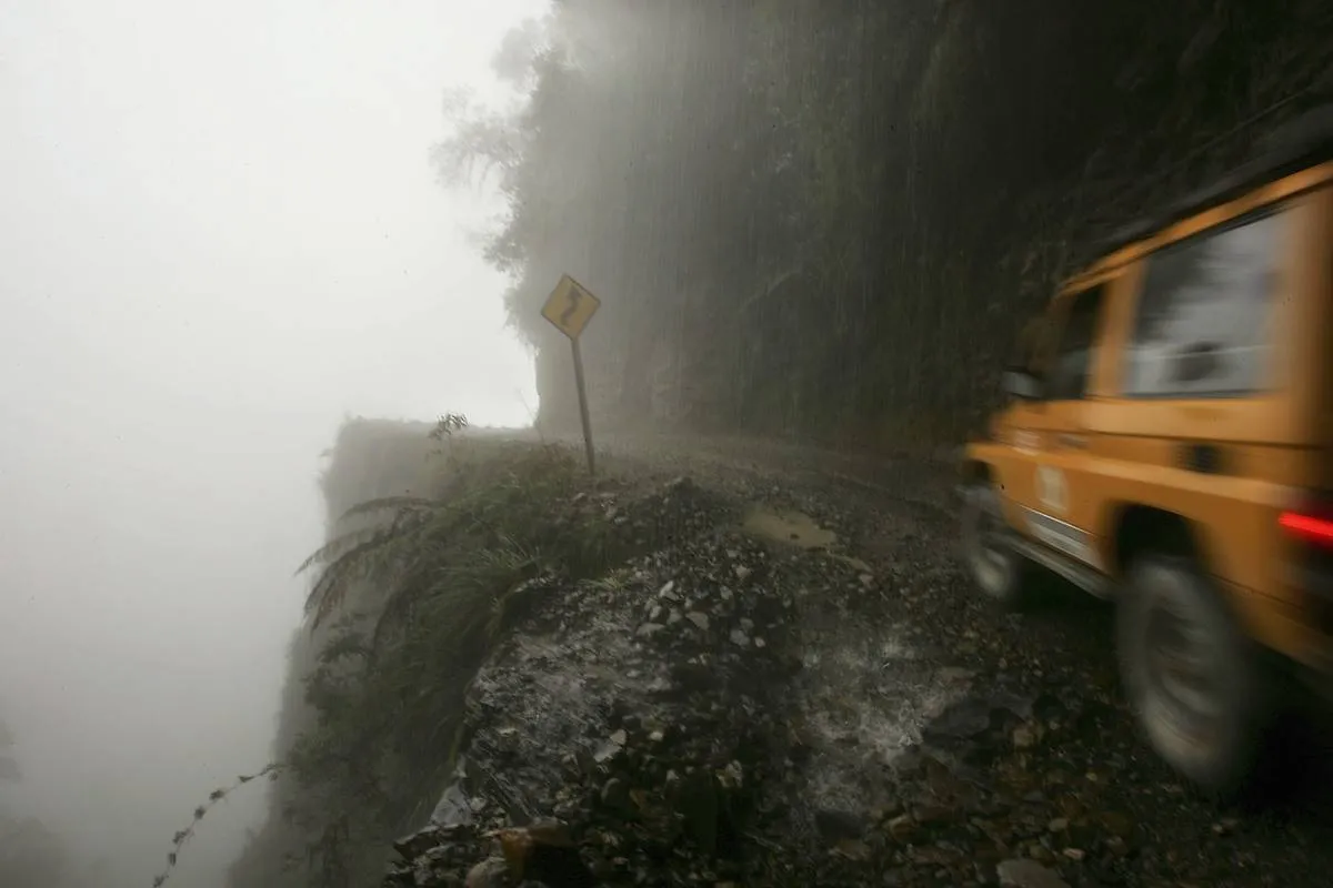 A car travels along the steep dirt road, North Yungas Road.