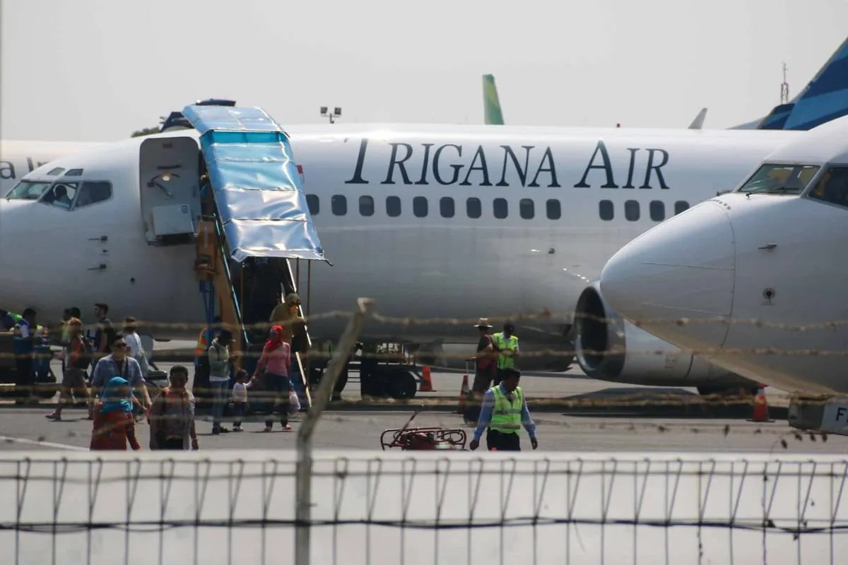 Passengers exist a Trigana Air plane.