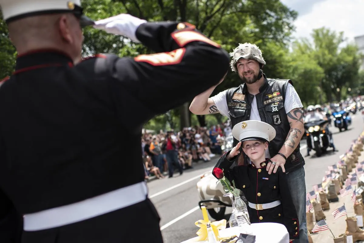 A father takes his son wearing a Marine uniform to salute Marine Staff Sgt. Tim Chambers, 