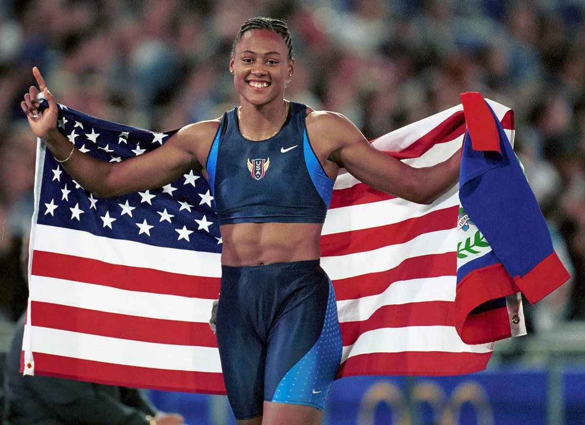 Marion Jones of the USA carries the American flag after winning the Womens 200M gold medal in a time of 21.84 seconds