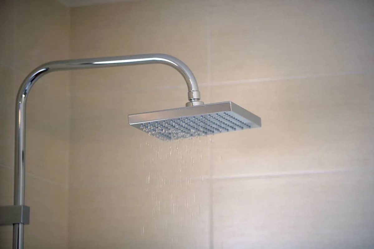 Close-up of a stainless steel shower with tiled wall