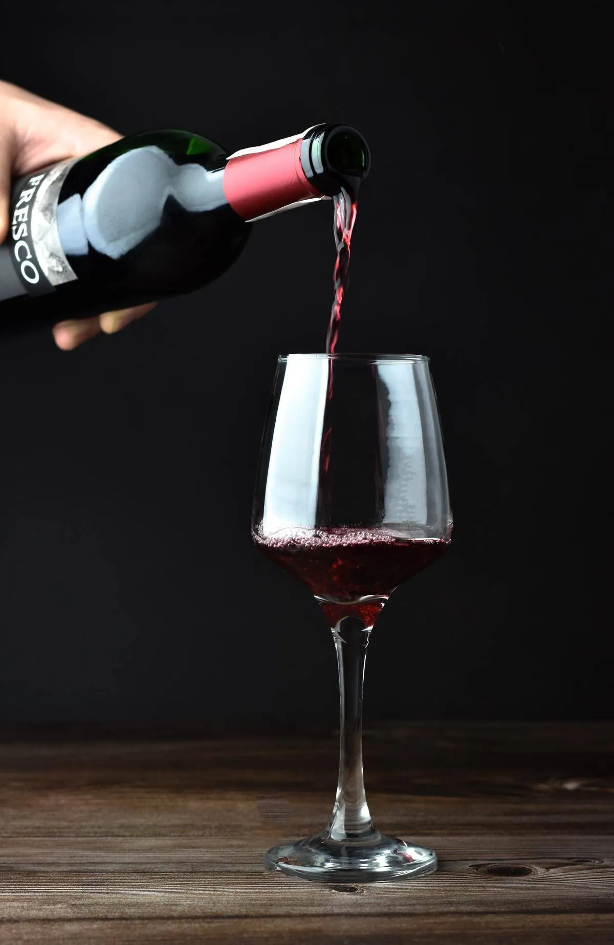 A glass of red wine being poured 