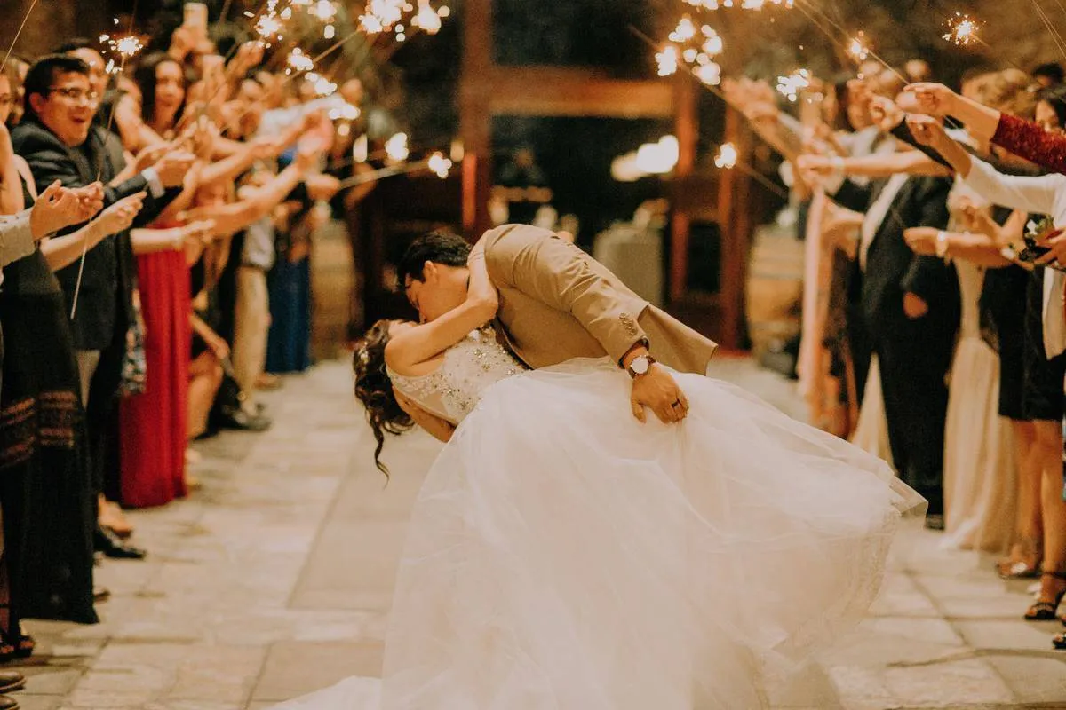 Newlyweds kiss among guests holding sparklers 