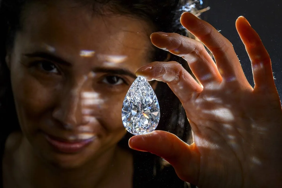 A model holds a diamond that is on sale for auction.