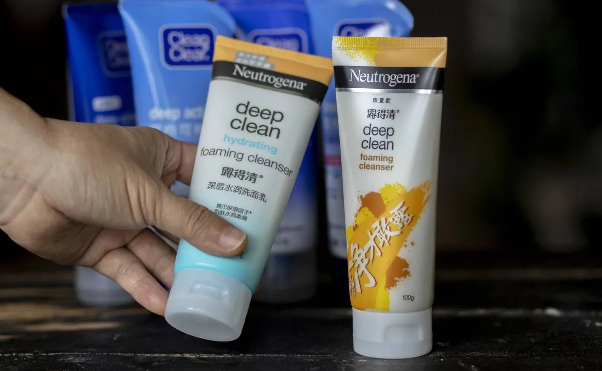 A person picks up a face foaming cleanser from a store shelf.