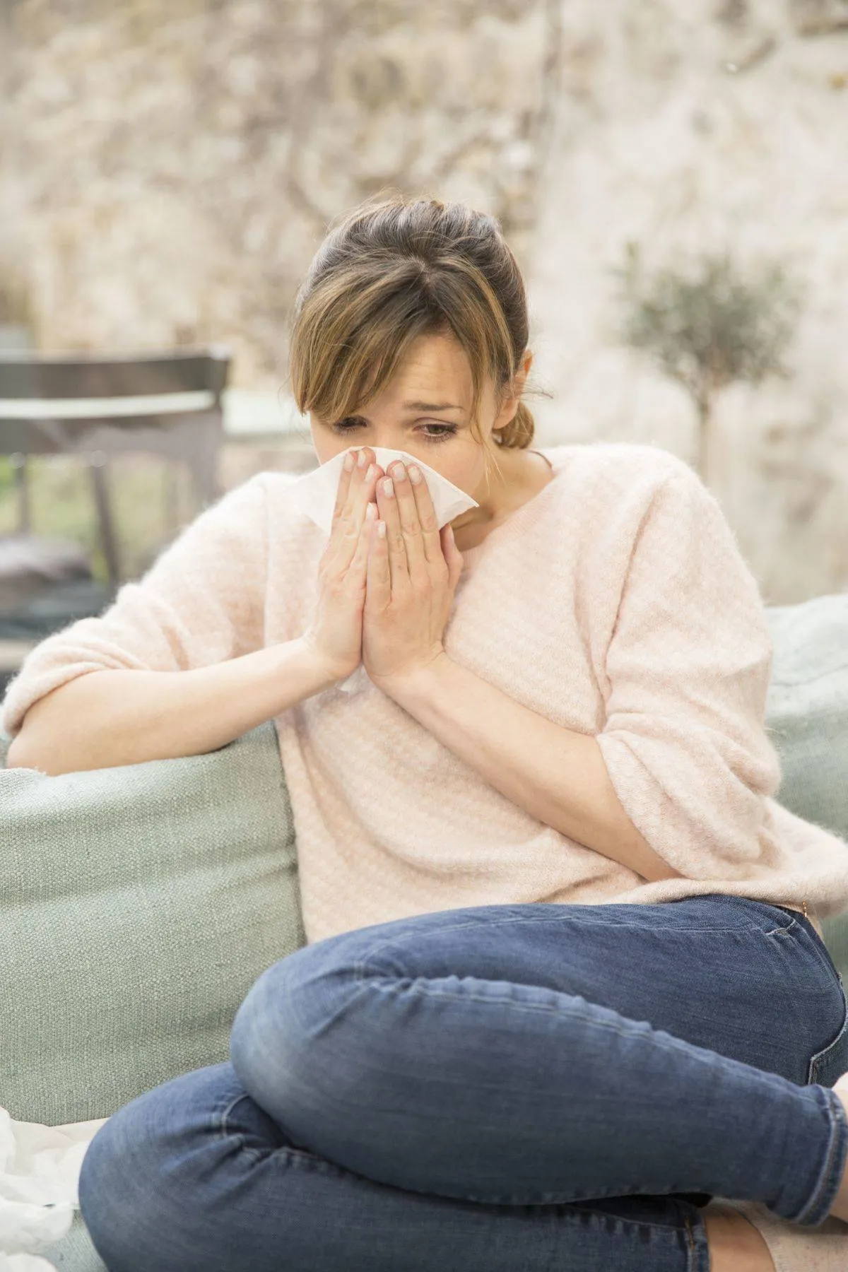 A woman blows her nose after sneezing.