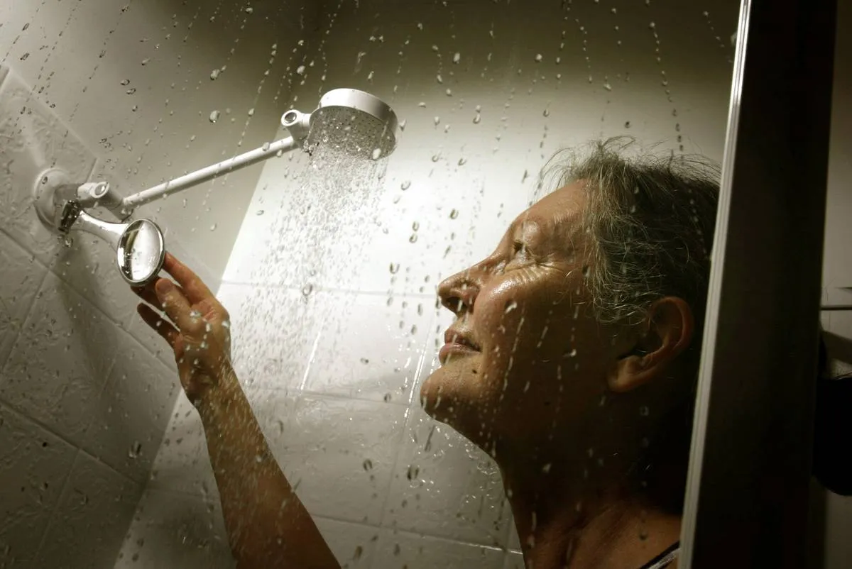 A woman adjusts the shower head during a shower.