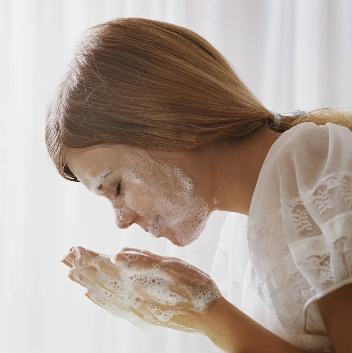 A woman washes her face with foaming soap.