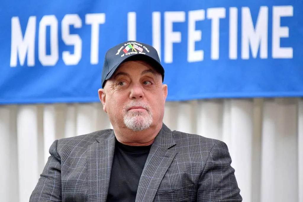 Billy Joel sits in front of the banner at a press conference