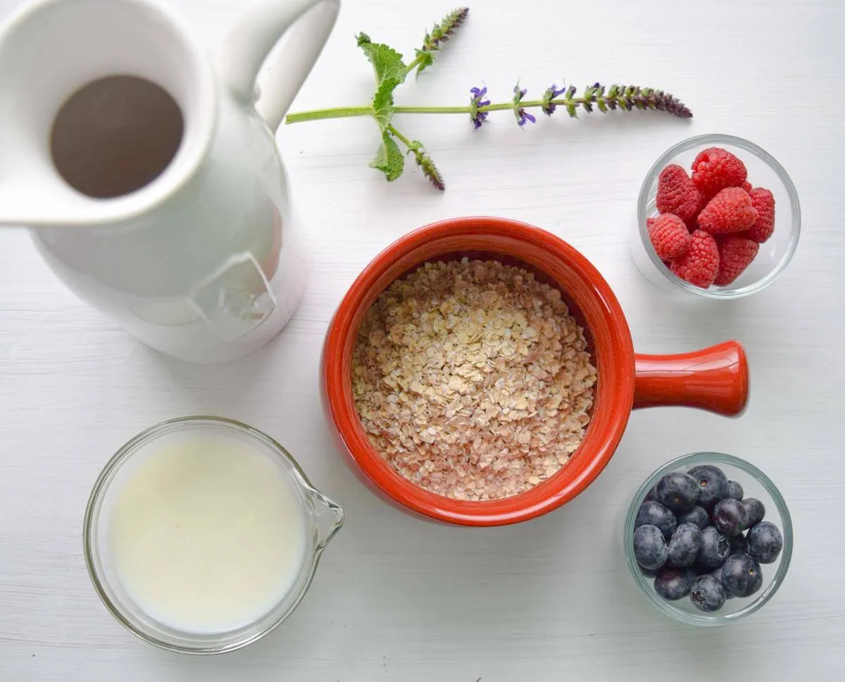 Bowls of milk, oatmeal, and juice on a table.