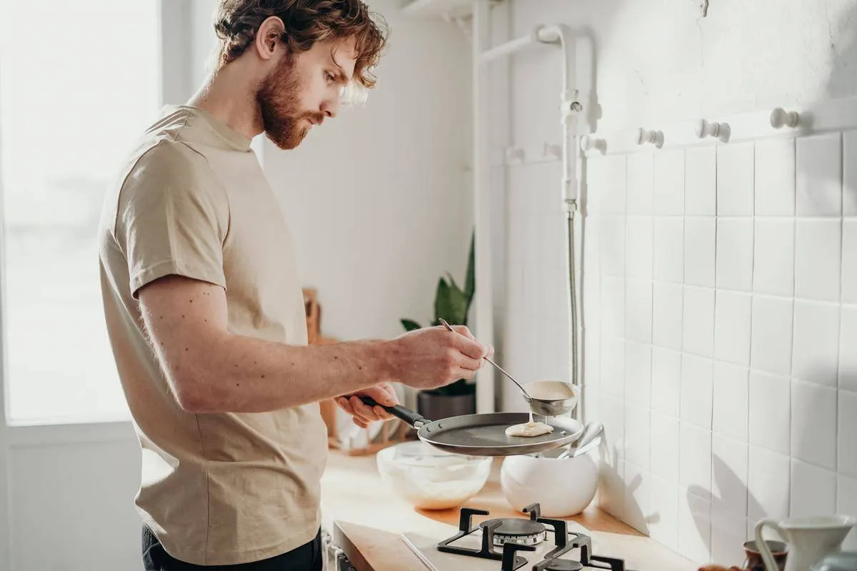 Man pouring pancake batter into a pan.