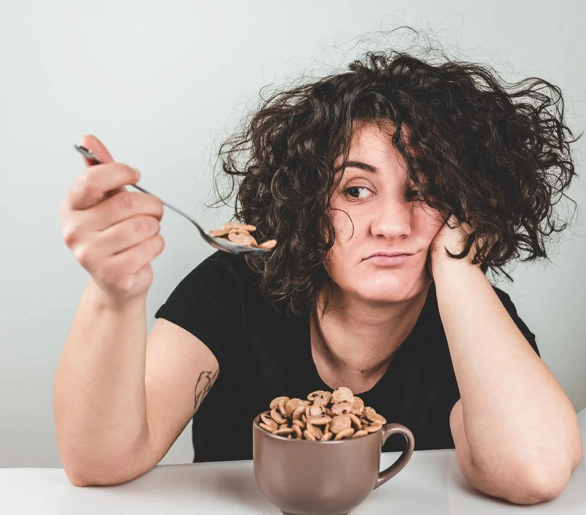 Woman looking skeptically at a spoonful of cereal.