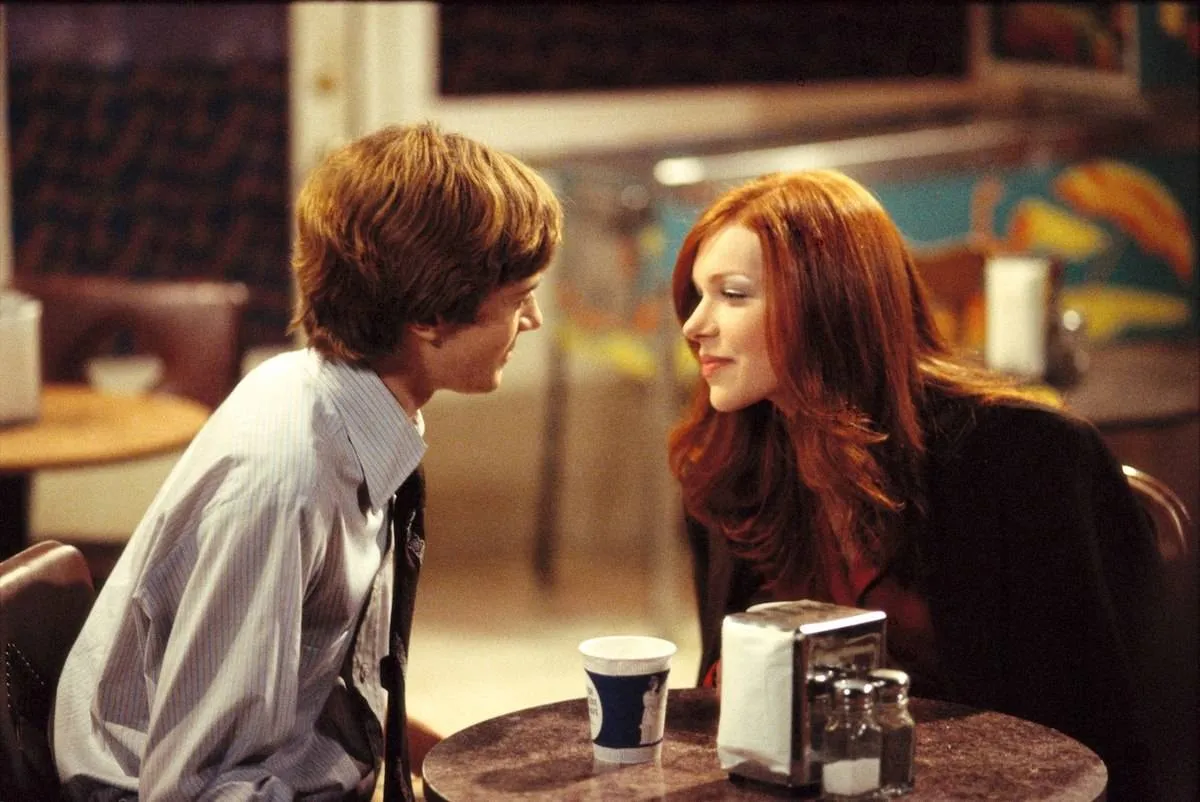 Laura Prepon and Topher Grace looking at each other at diner table as Donna Pinciotti and Eric Forman in That '70s Show