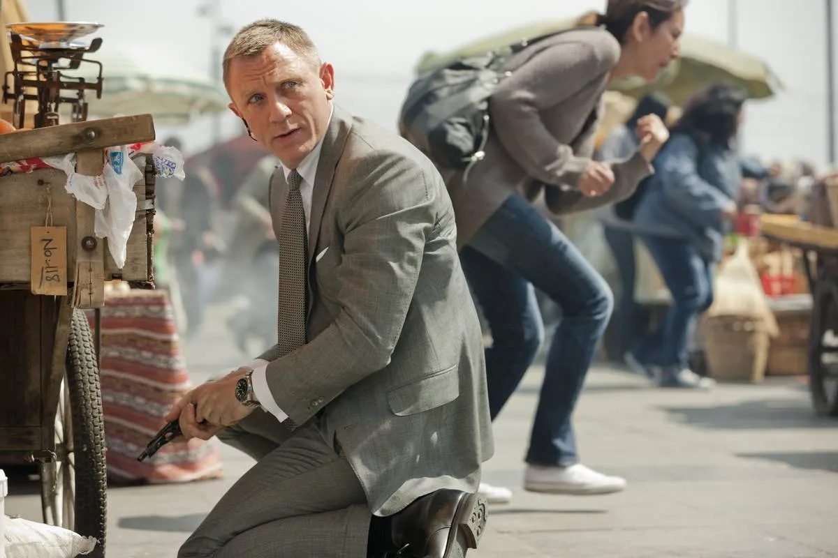 Daniel Craig kneeling on street with empty pistol as James Bond in Skyfall