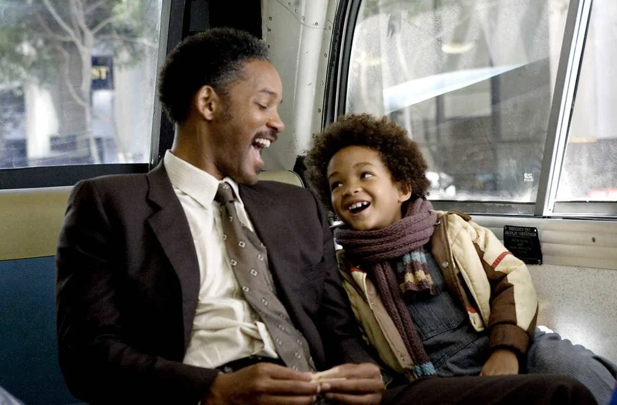 Will Smith as Chris Gardner laughing with Jaden Smith as Christopher Gardner on bus in The Pursuit of Happyness