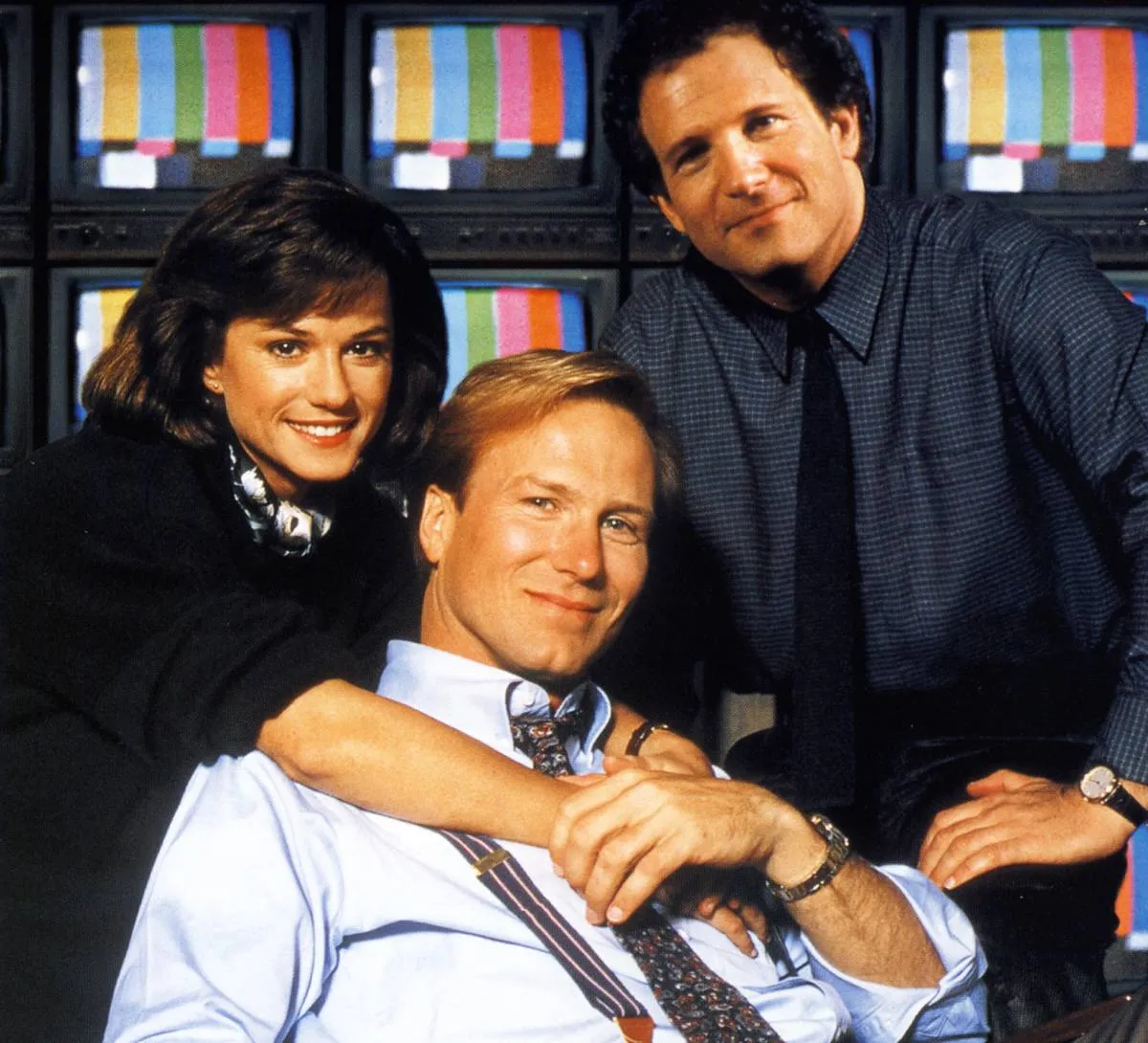 cast of broadcast news in front of tv's with colored stripes
