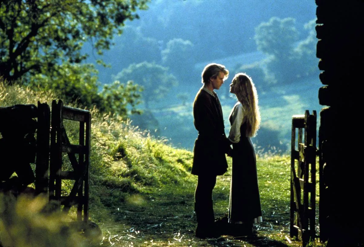 man and woman facing each other in a farm field in the princess bride