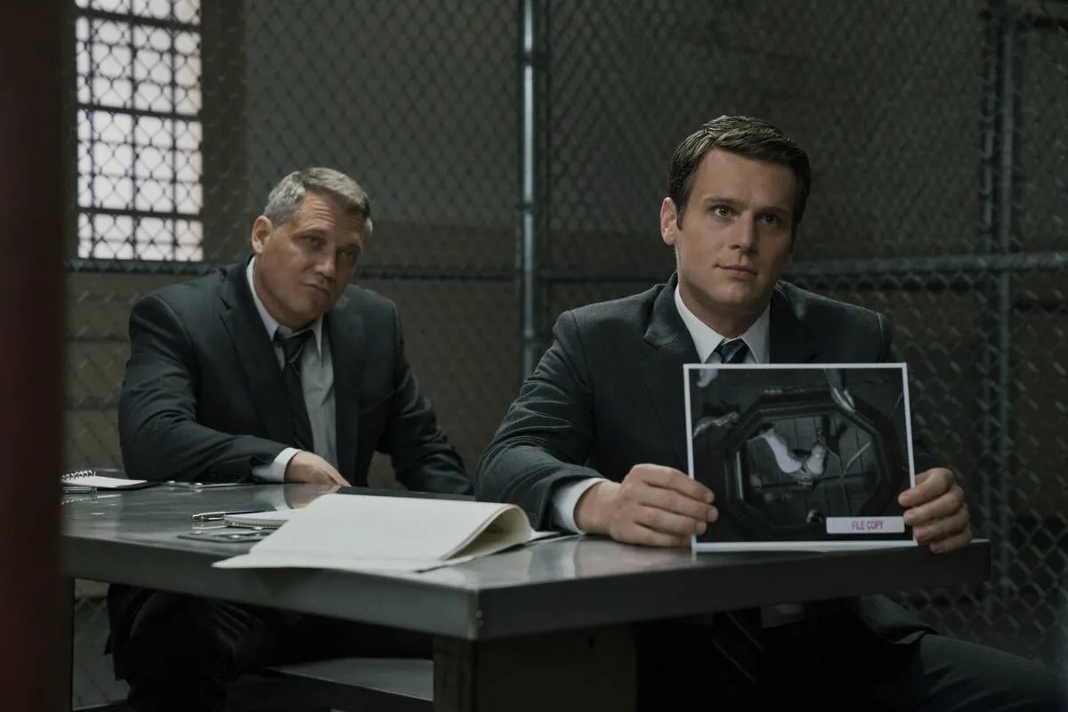 Jonathan Groff holds up image as Holden Ford while Holt McCallany looks on as Bill Tench in Mindhunter