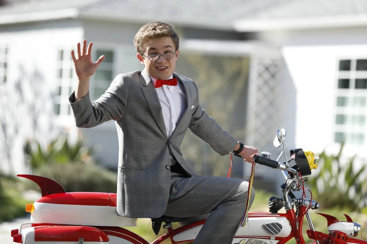 Sean Giambrone waving on bike in Pee Wee Herman outfit as Adam Goldberg in The Goldbergs