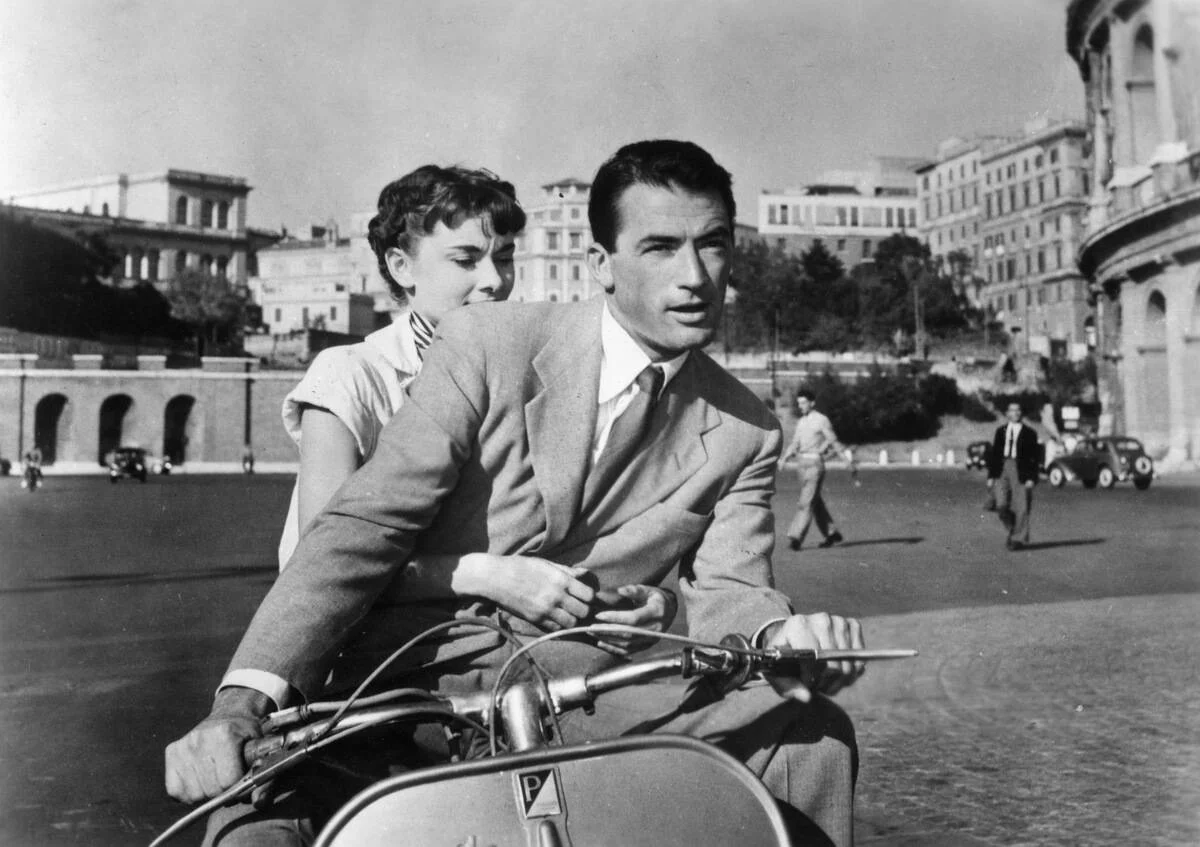 Gregory Peck and Audrey Hepburn riding vespa in [redacted]