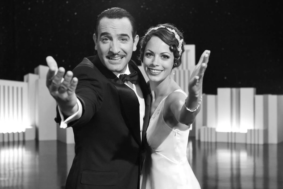 Jean Dujardin and Bérénice Bejo smiling in [redacted]